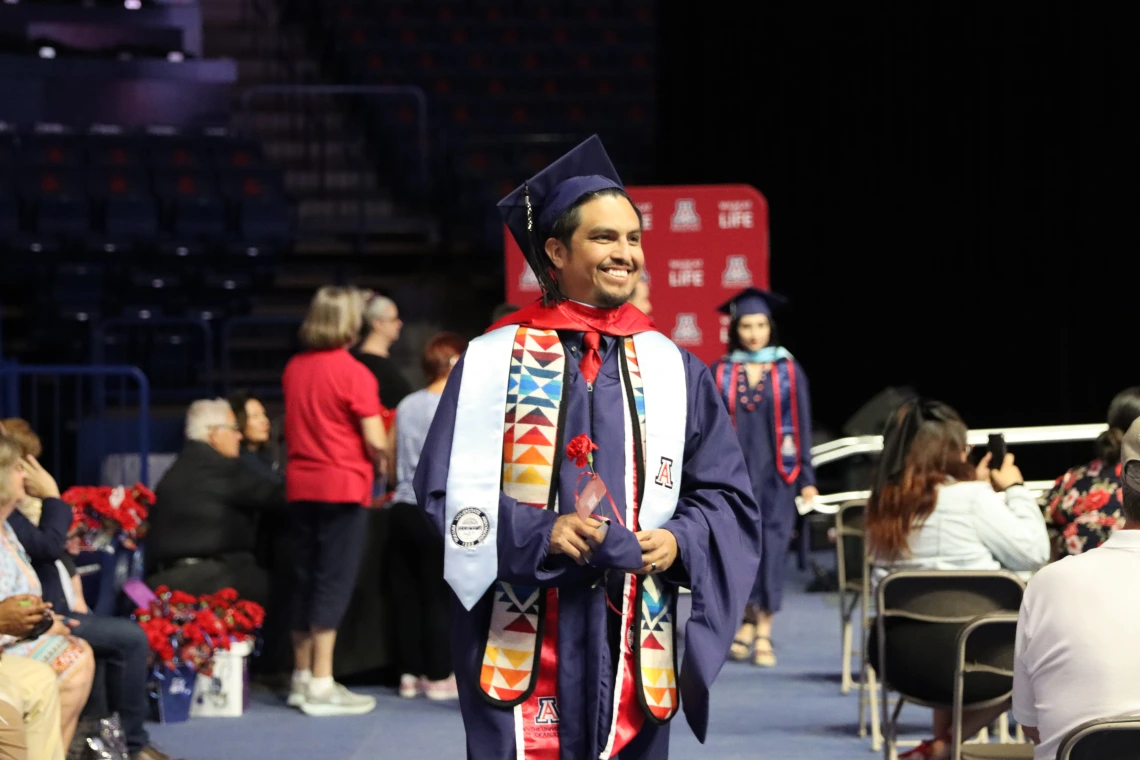 graduate in full regala walking in convocation ceremony