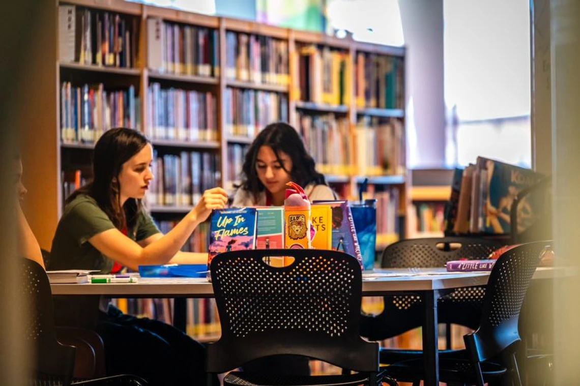 adult and child sitting at a table in a library