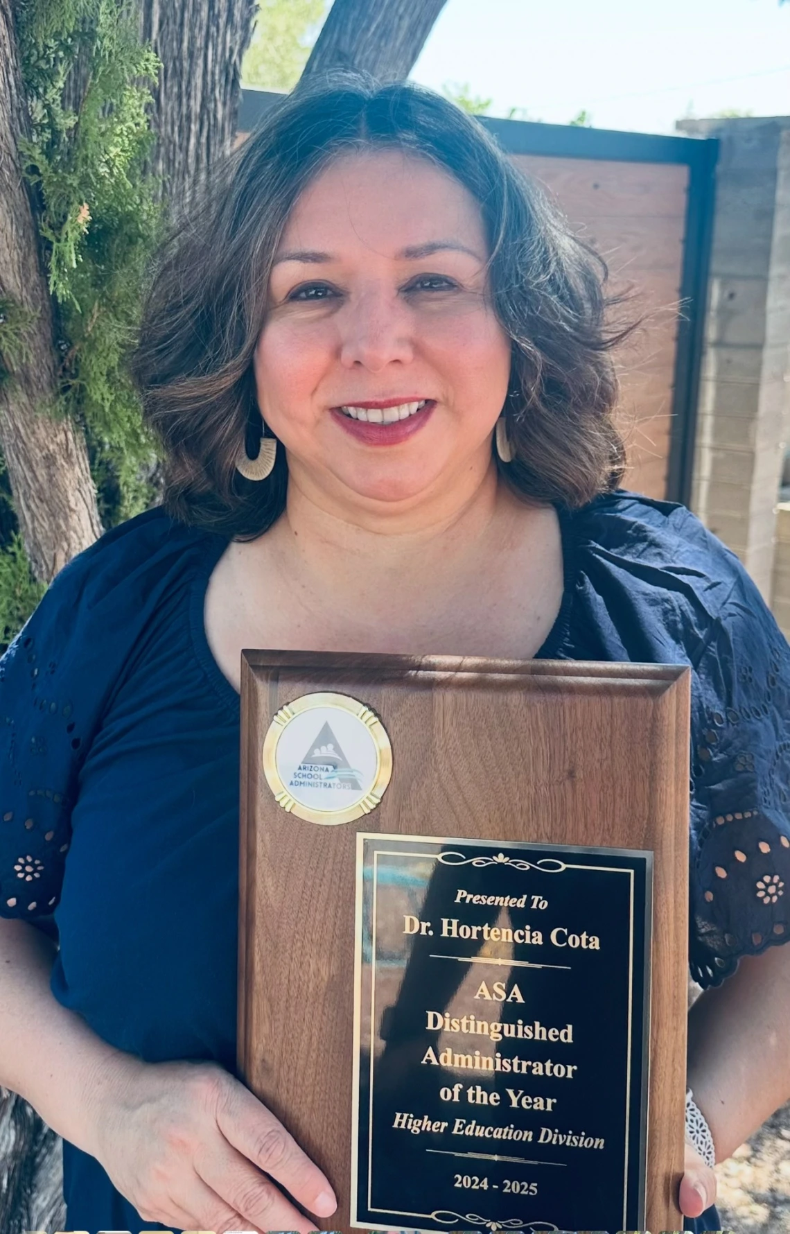 Dr. Hortencia Cota smiling while holding her 2024–2025 ASA Distinguished Administrator of the Year award for the Higher Education Division, presented by Arizona School Administrators.