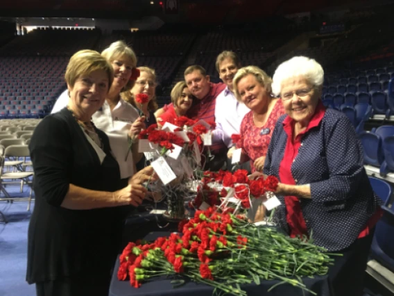 alumni council group photo in auditorium, preparing red carnations for ceremony