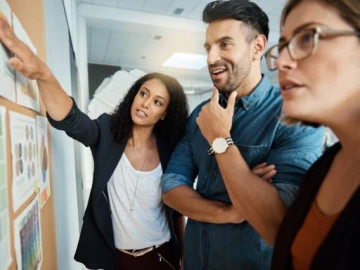 three young adults conversing while looking at an informational board