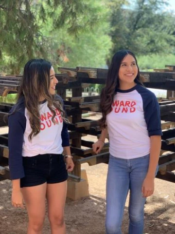 two young female students wearing updward bound shirts standing in the outdoor sun