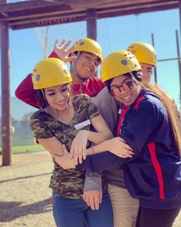 group of students hugging wearing helmets doing an outdoor activity