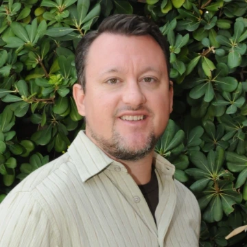 michael hartley standing outside with greenery in the background