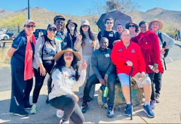 Group photo, outside under sunny sky, desert mountains in the distance