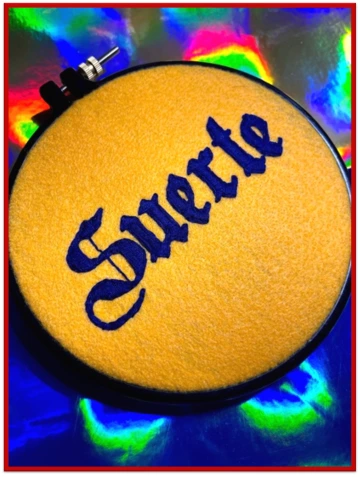 Round felt with the word "Suerte" embroidered into it