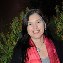 iliana reyes, medium length dark hair, gray blouse, black jacket with a red scarf