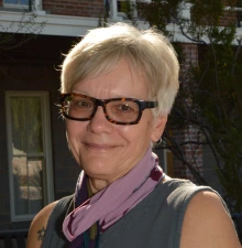 suek headshot, wearing eyeglasses, outdoor under a sunny sky