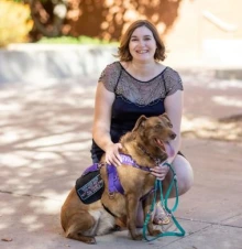 megan mcdevitt sitting outside under a shady tree with a service dog