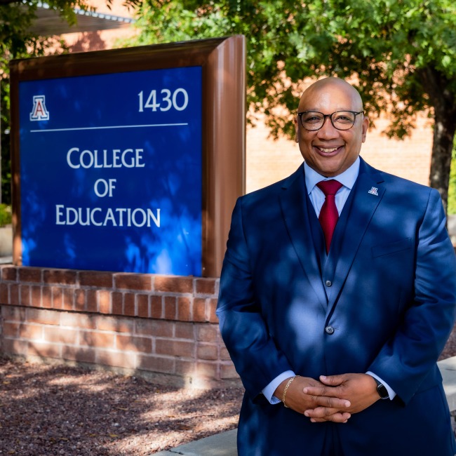 robert berry, dean of college of education, male black man standing under a shaded tree next to the college of education sign